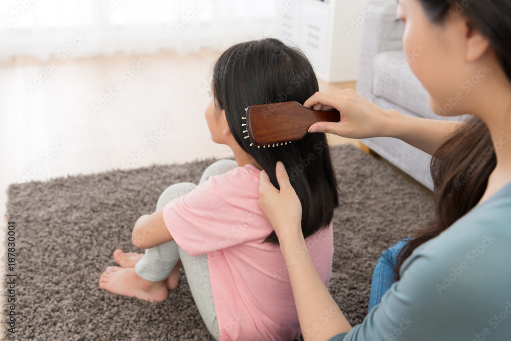 年轻女子用刷子梳理小女孩的头发