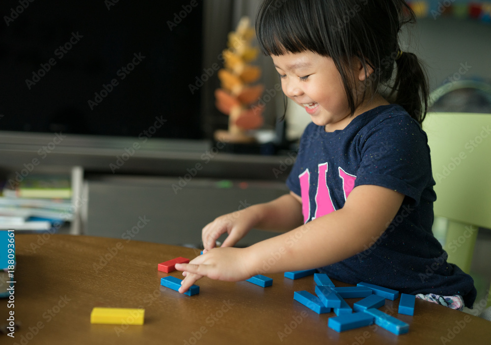 小女孩在不稳定的塔楼上玩木块。建筑倒塌游戏。孩子们想象