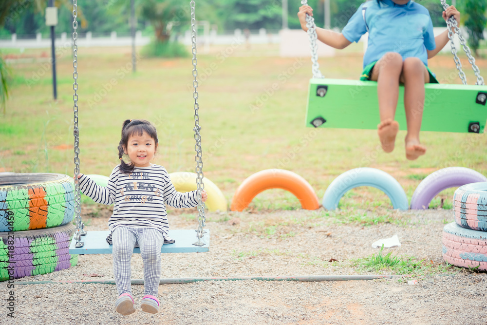 Adorable girl having fun on a swing on summer day