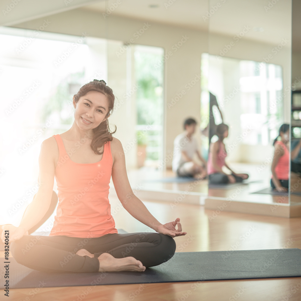 Attractive young Asian woman group exercising and sitting in yoga lotus position in yoga classes. as