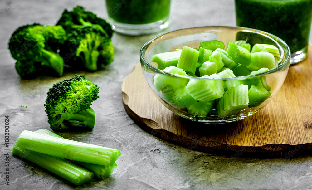 Green vegetable smoothie in glass at gray background