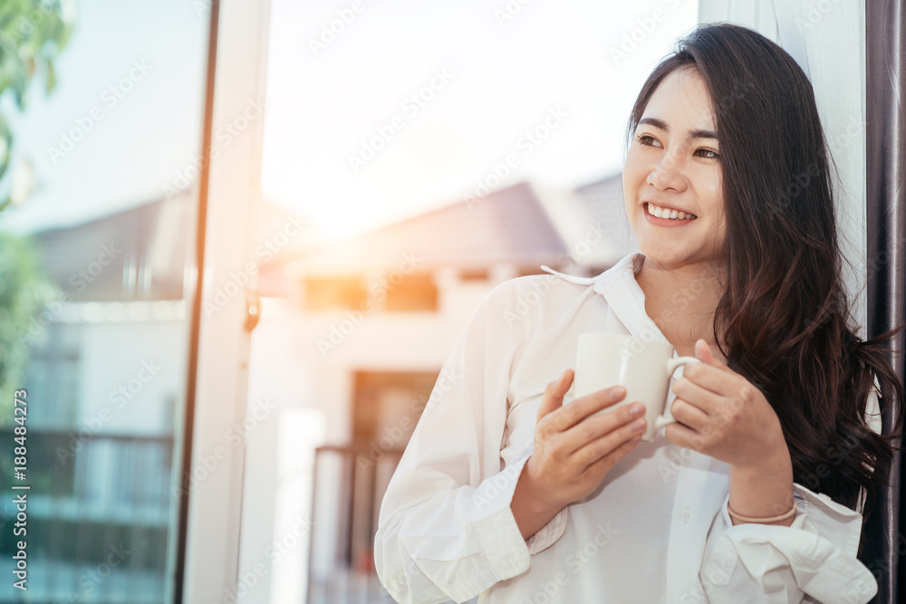 早上刚醒来的亚洲女孩很放松。她打开窗户接受阳光