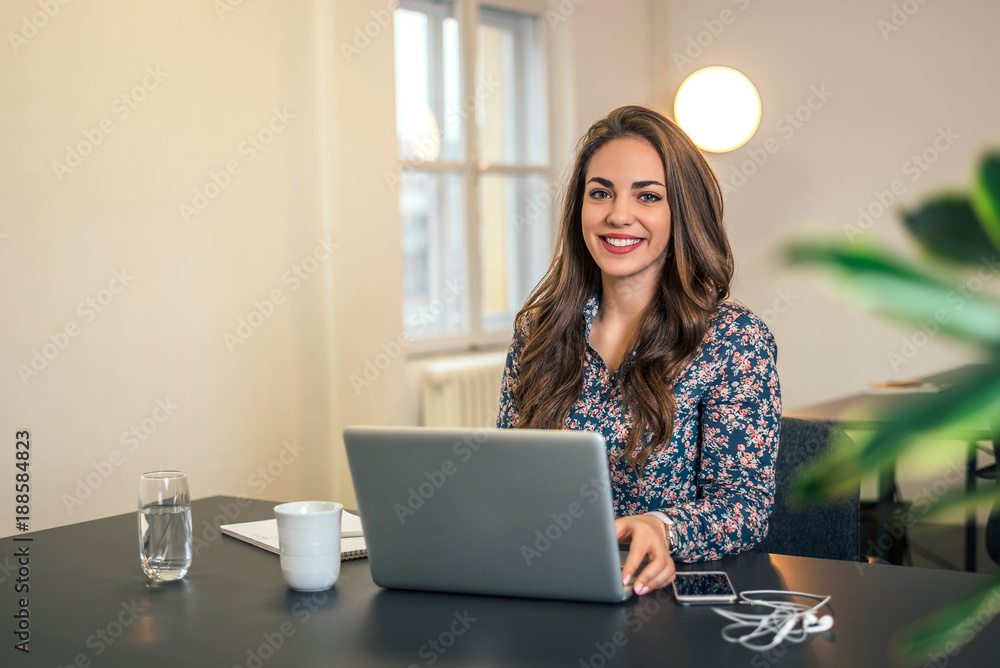 Young attractive businesswoman in modern office working on laptop.