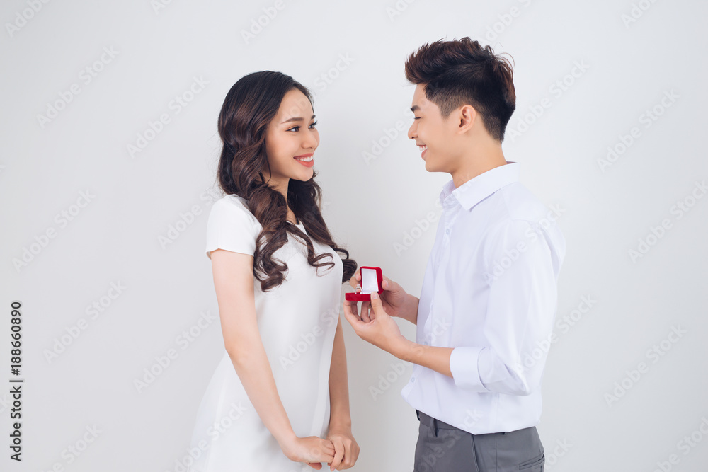 Happy beautiful Vietnamese girl looking at her boyfriend and smiling while getting a marriage propos