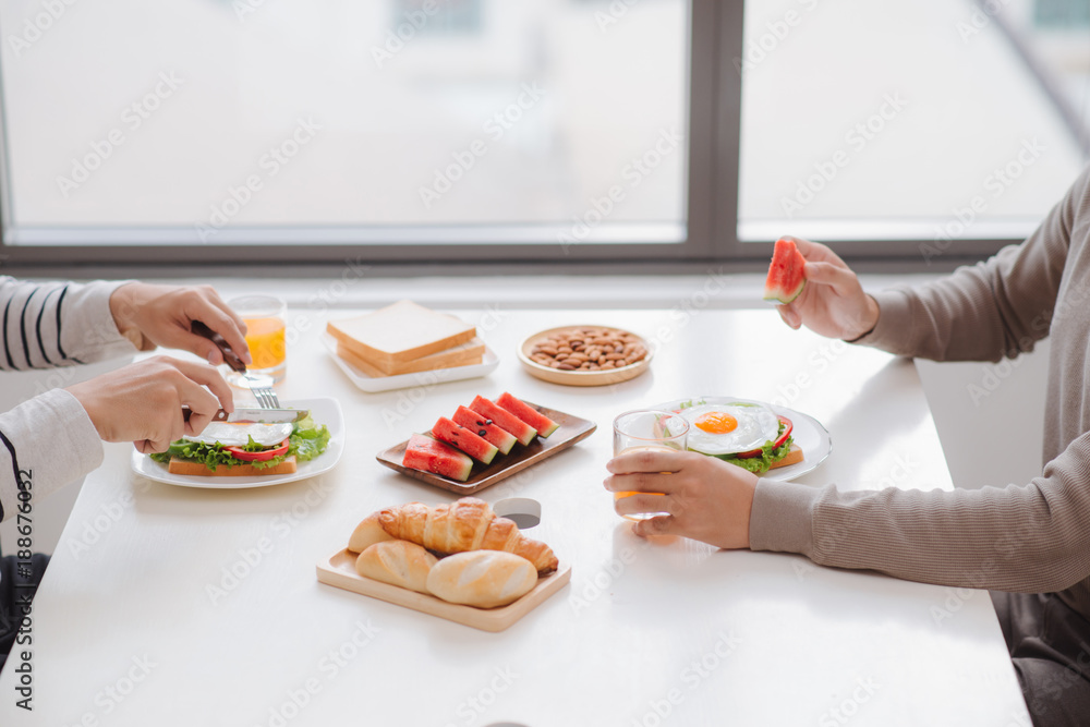 Two male friends eating breakfast at home in morning.