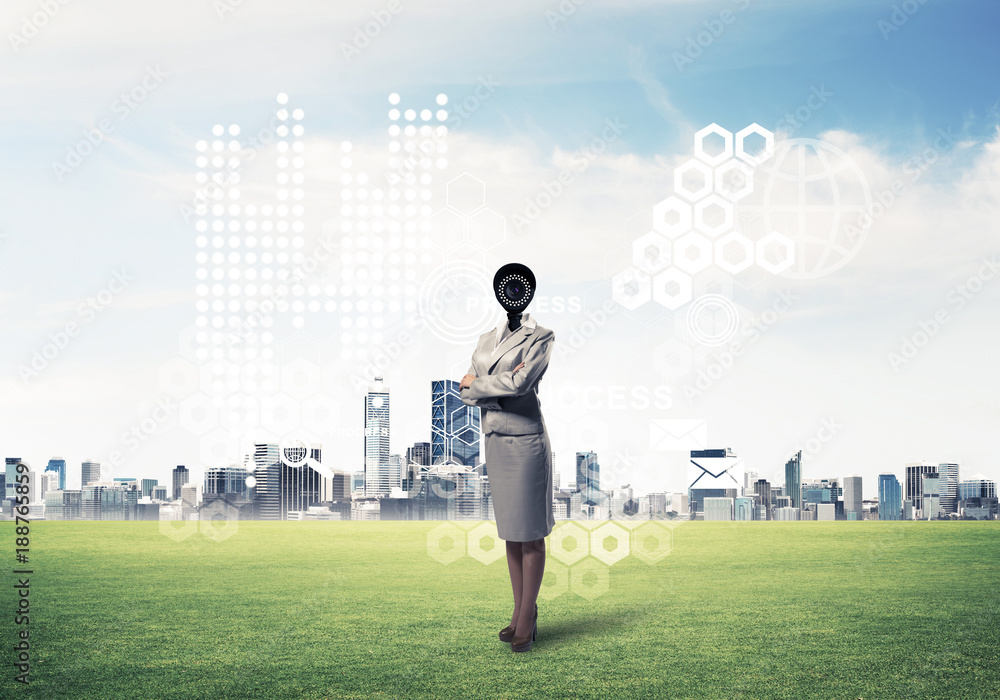 Camera headed woman standing on green grass against modern citys