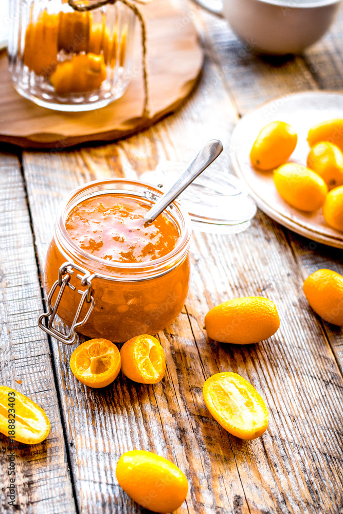 kumquat on plate and jam in jar at wooden table