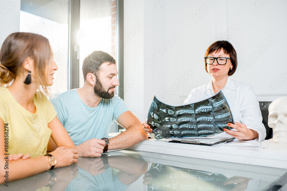 Young couple having a consultation with senior doctor discussing x-ray print sitting in the white of