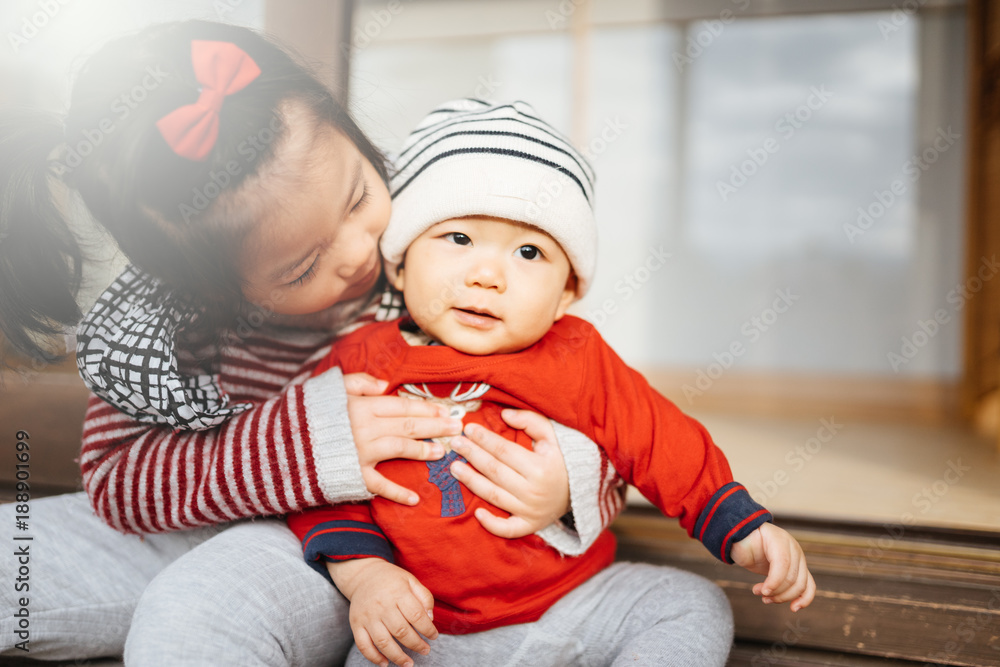 小妹妹拥抱她的小弟弟。蹒跚学步的孩子遇到了新的兄弟姐妹。可爱的女孩和男婴放松