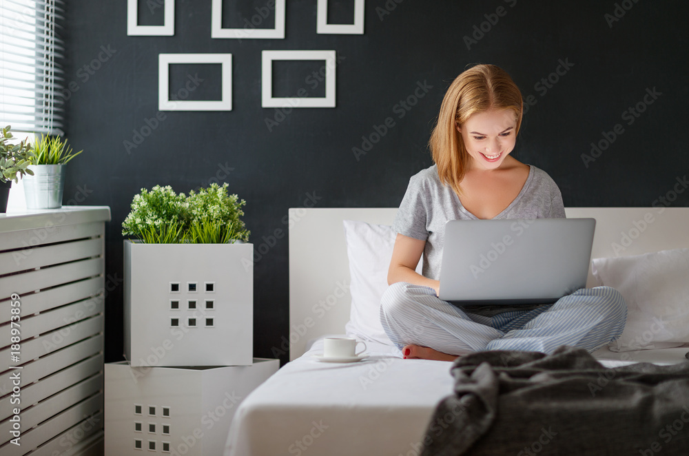 young beautiful woman with  laptop and  cup of coffee in   morning in bed