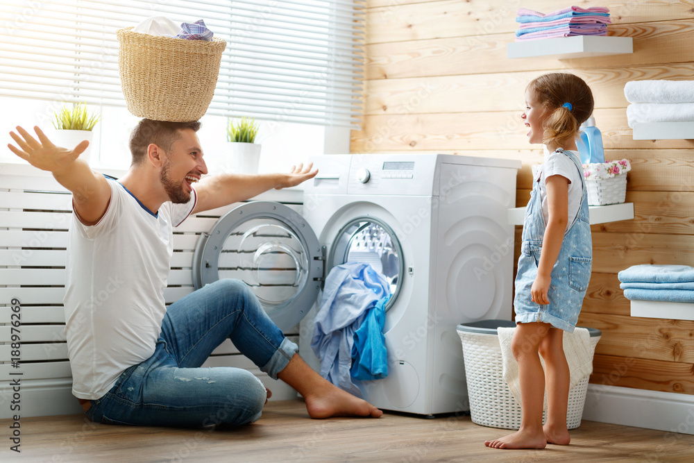 Happy family man father householder and child   in laundry with washing machine