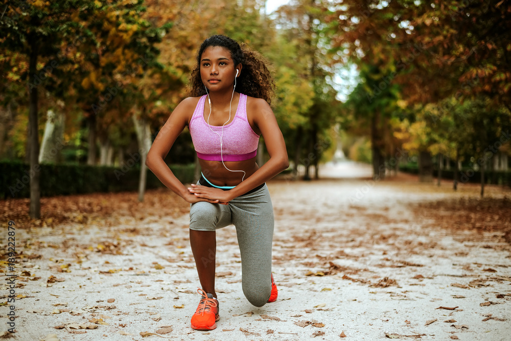 Young female runner with beautiful figure doing stretching exercise before jogging.