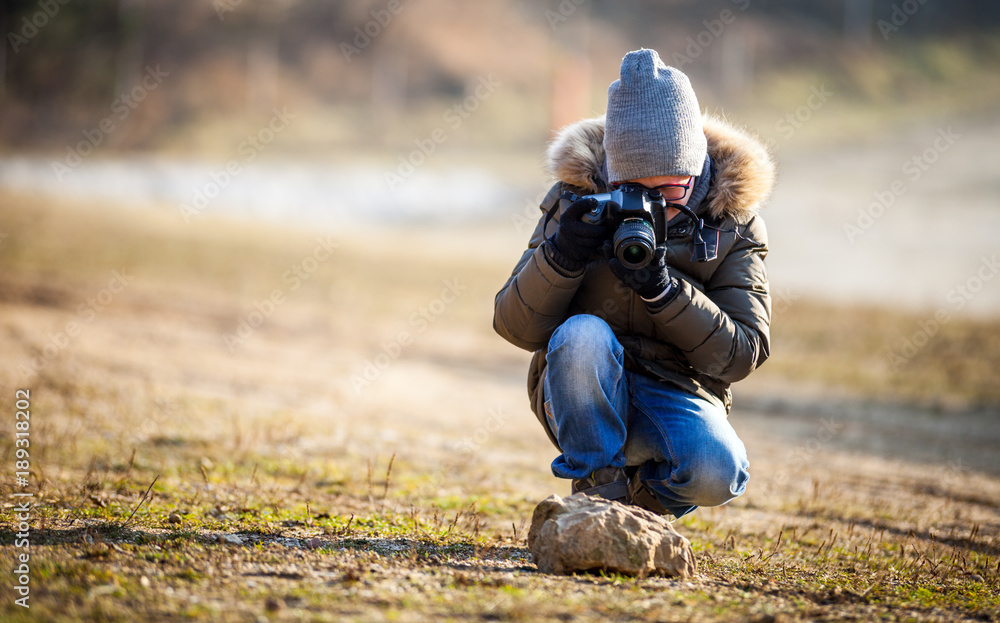 Boy using digital camera taking photo in the nature, hobby concept