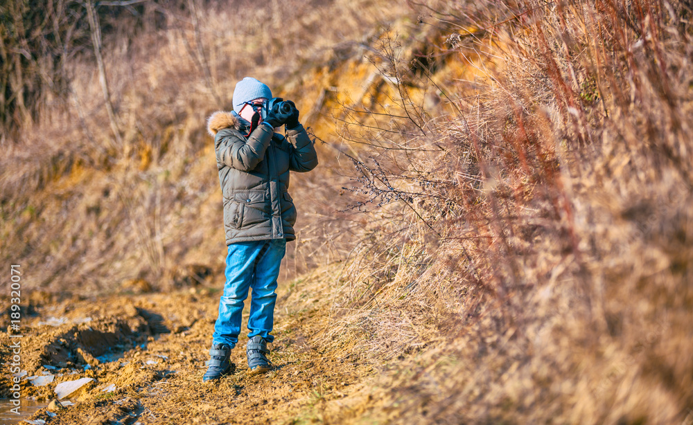 Boy using digital camera taking photo in the nature, hobby concept