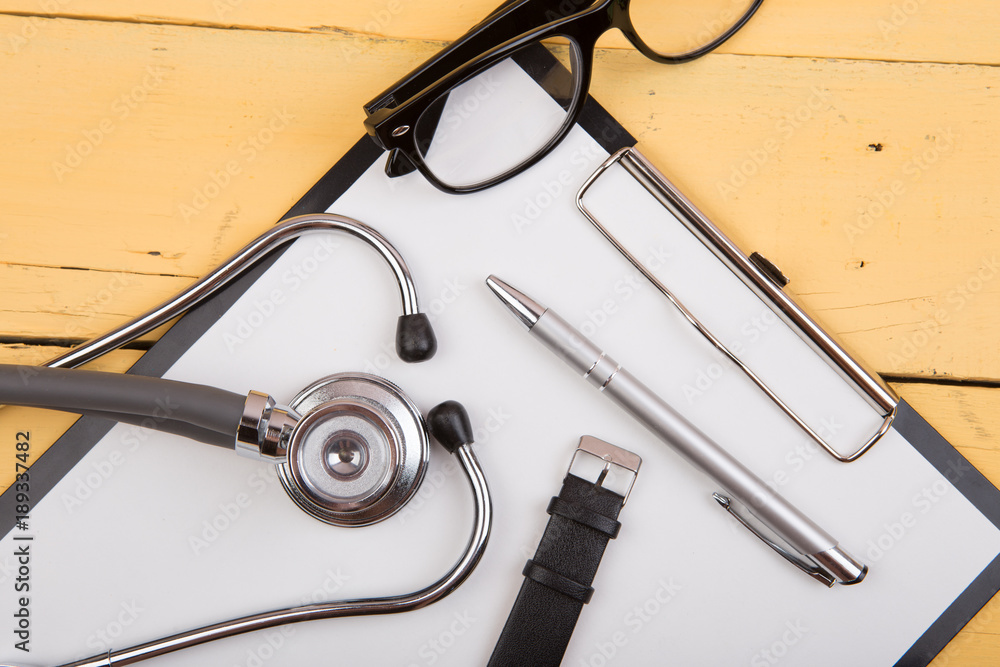 Workplace of doctor - stethoscope and other supplies on the yellow wooden desk