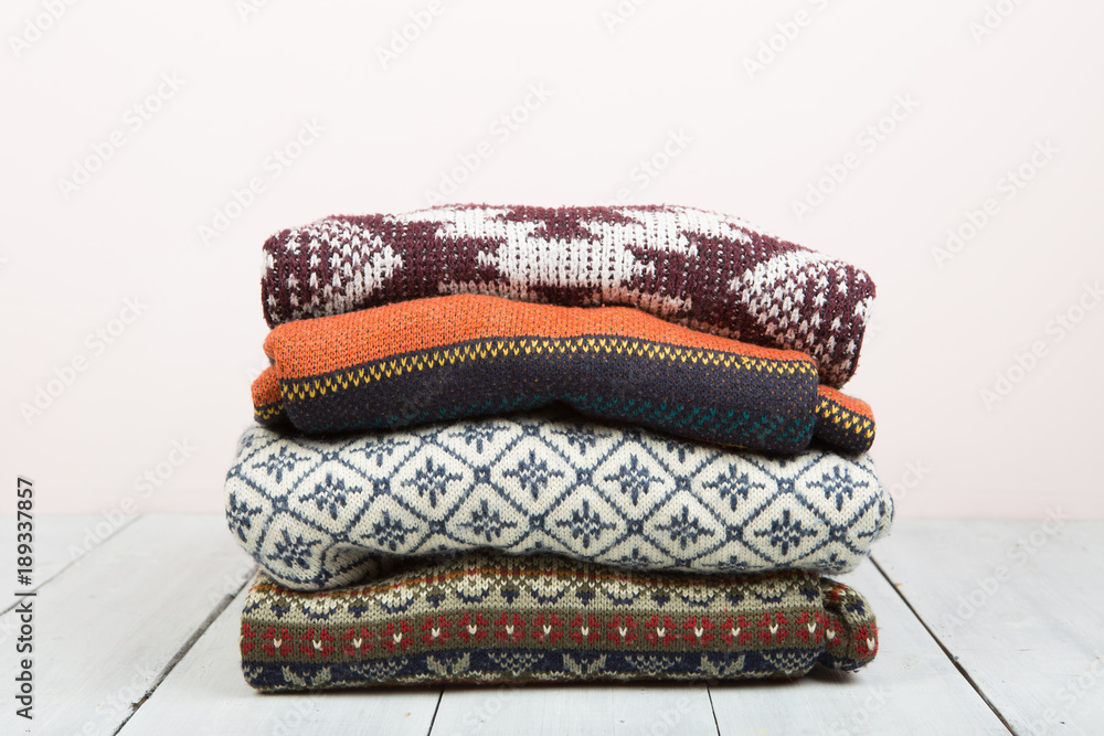 Pile of knitted winter sweaters on wooden background