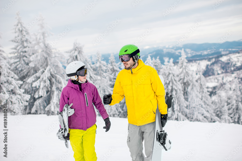 Young couple walking with snowboards during the winter vacation on the snowy mountains