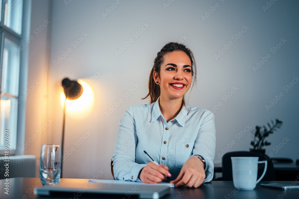 Businesswoman at workplace writing business tasks at personal organizer.