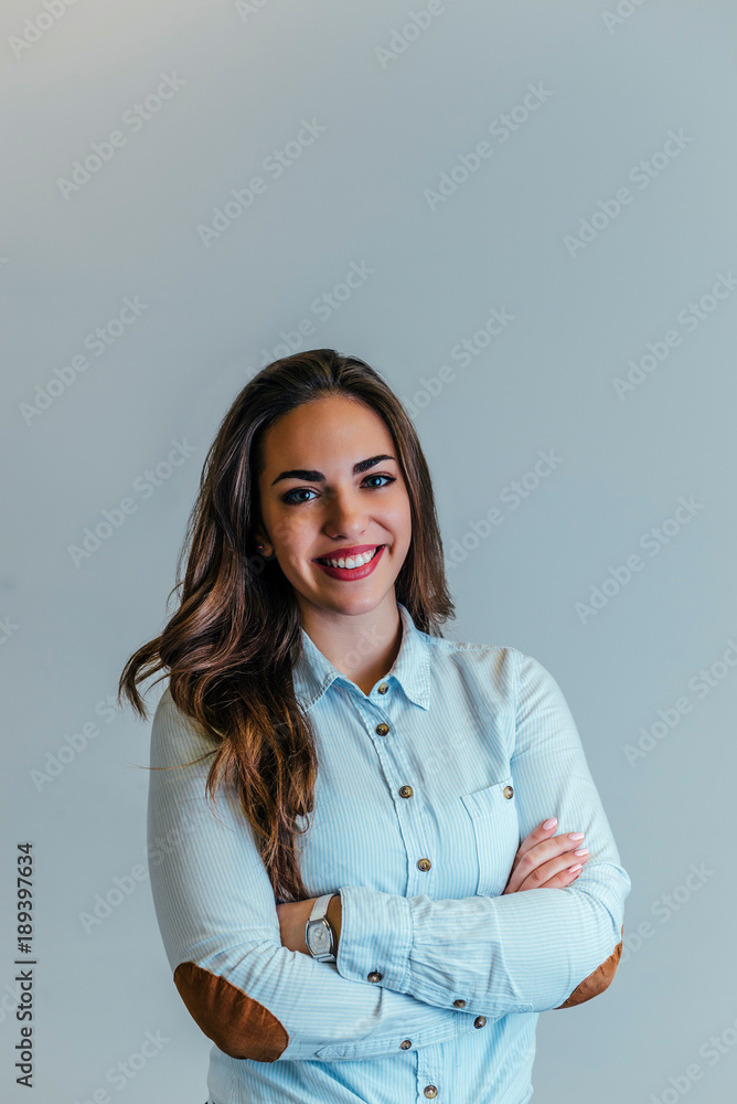 Studio shot of blond young woman with arms crossed isolated.