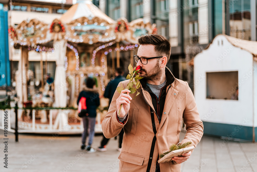 Handsome romantic happy man holding and smelling rose.