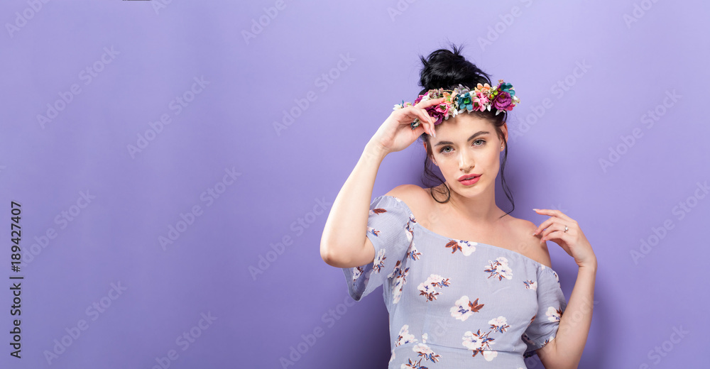 Beautiful young woman with a garland on a solid background