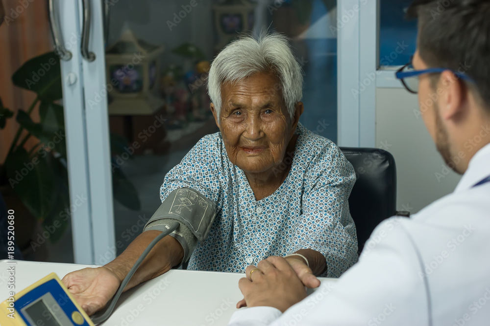 Male Doctor listening heart beat and breathing of Elderly Woman with Stethoscope with First Aid Medi