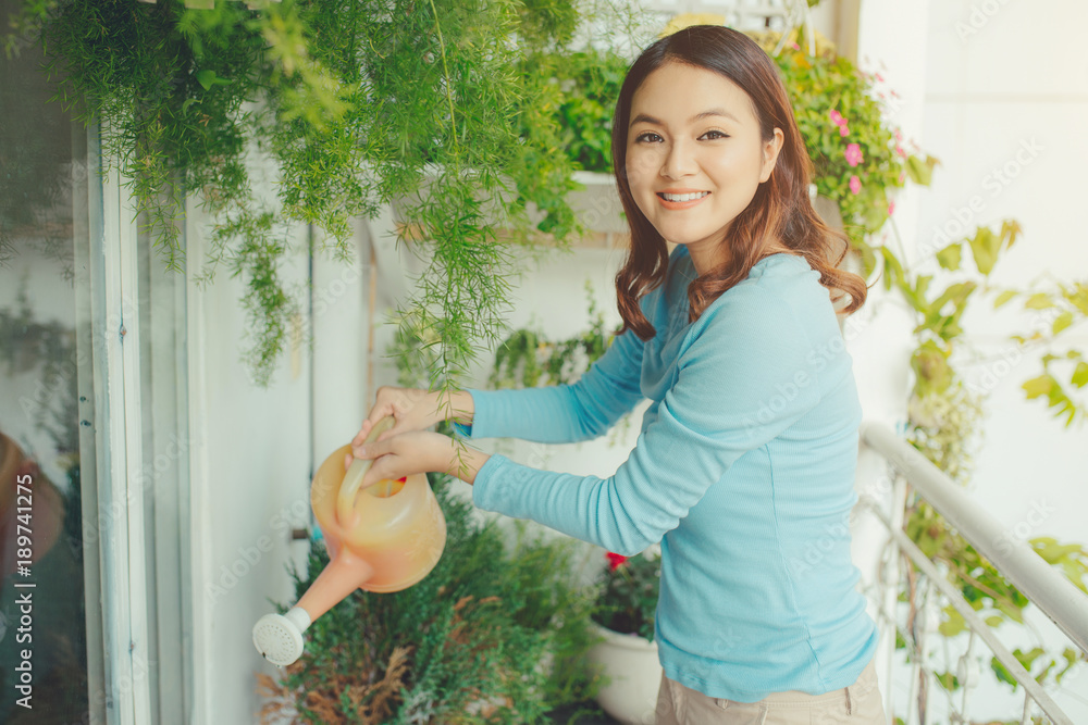 妇女在阳台花园的容器中给植物浇水