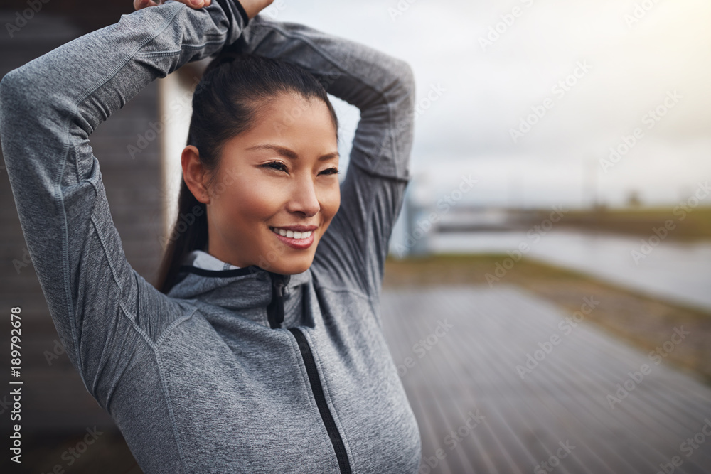 Smiling Asian woman in sportswear stretching before exercising o