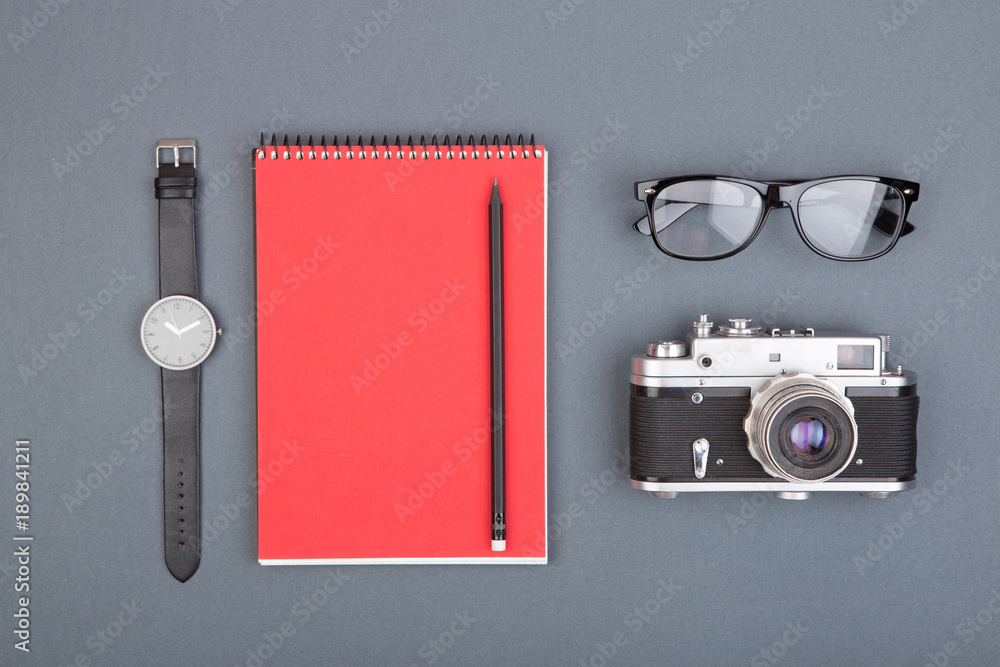 Journalist or blogger table - spiral blank notebook, pencil, camera and glasses on gray background, 