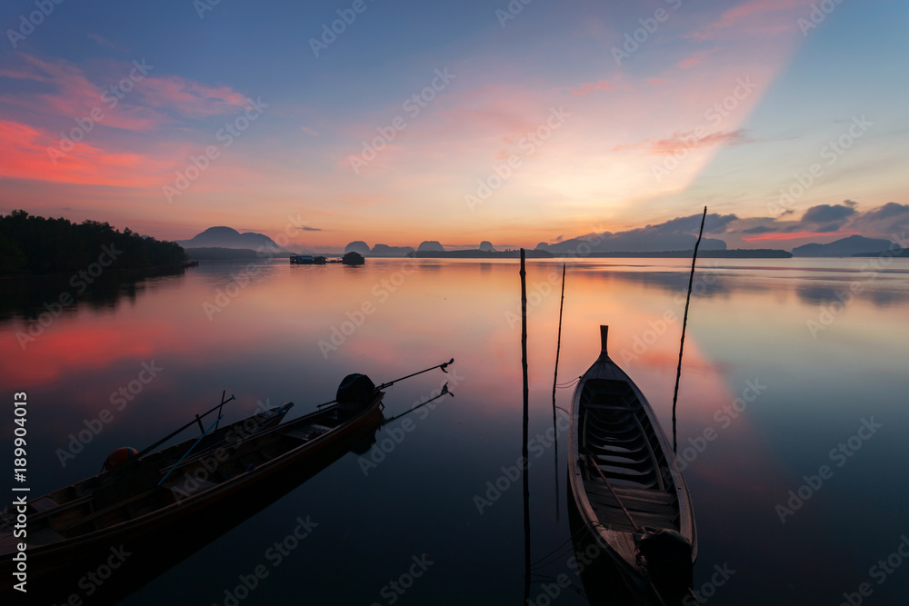 Longtail boat with coastal fishing village,Beautiful scenery view in morning sunrise over sea and mo