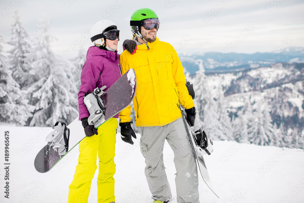 Young couple walking with snowboards during the winter vacation on the snowy mountains