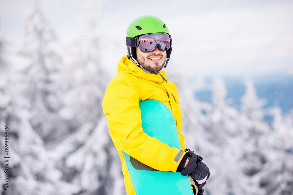 一个穿着冬季运动服的男人在山上拿着滑雪板的肖像