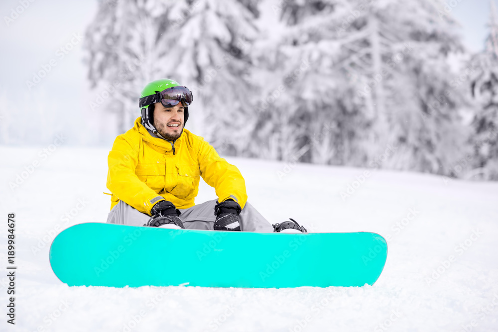 男子在雪山户外骑行后，坐在滑雪板上休息