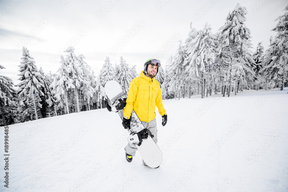 身穿黄色冬装的男子在雪山上滑雪板行走