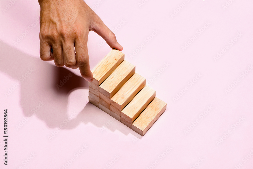 Concept of building success foundation. Male hand put wooden blocks in the shape of a staircase