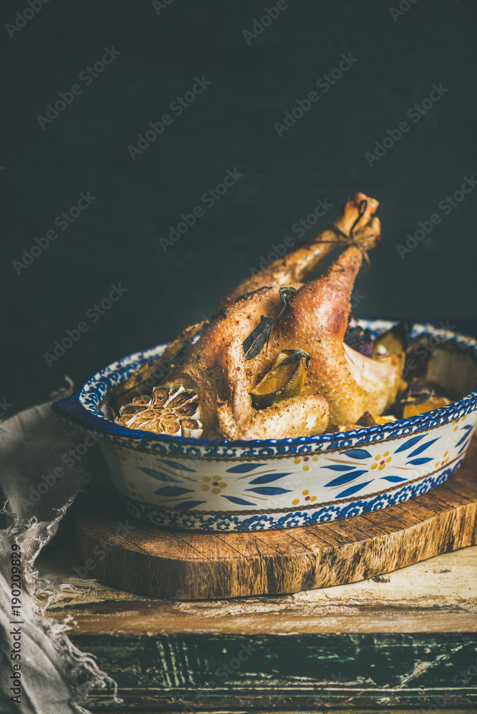 Roasted whole chicken for Christmas eve celebration table on rustic wooden board, black wall backgro