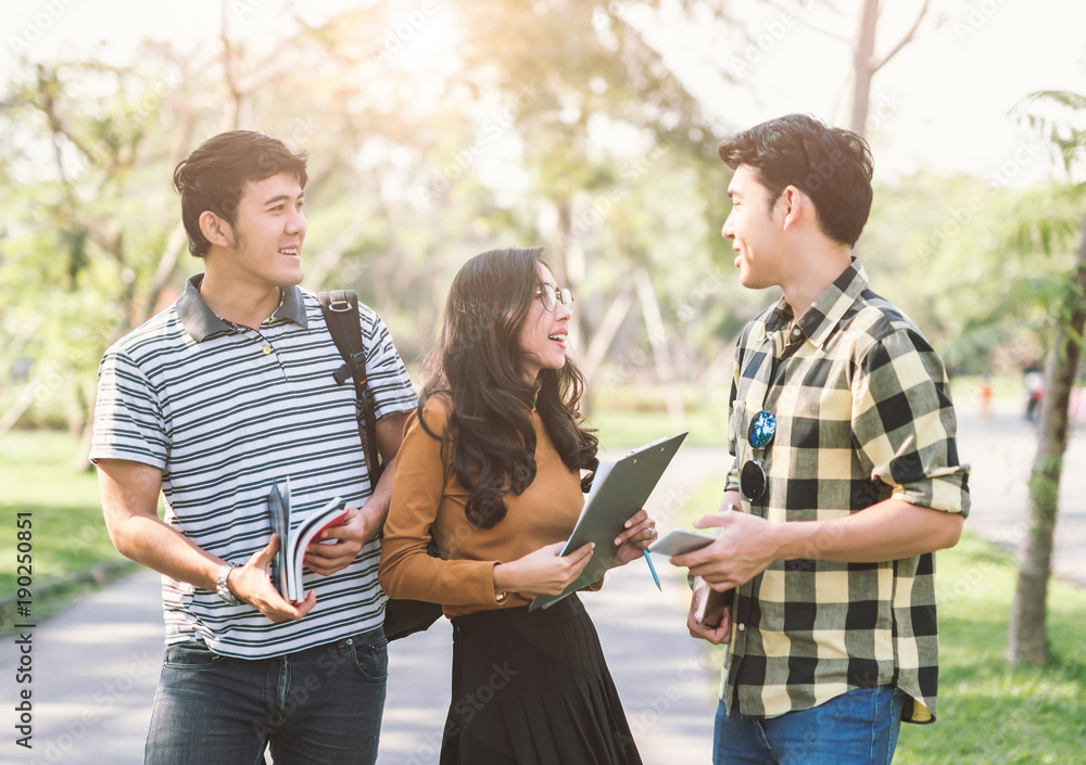 happy students walking and talking each other in a campus at park with a warm light