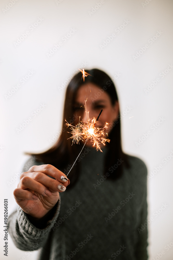 一个模糊的女人在孤立的背景上拿着闪闪发光的棍子。