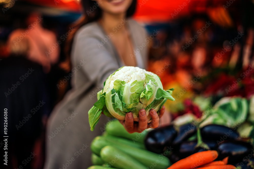 Woman holding cauliflower at farmers market.