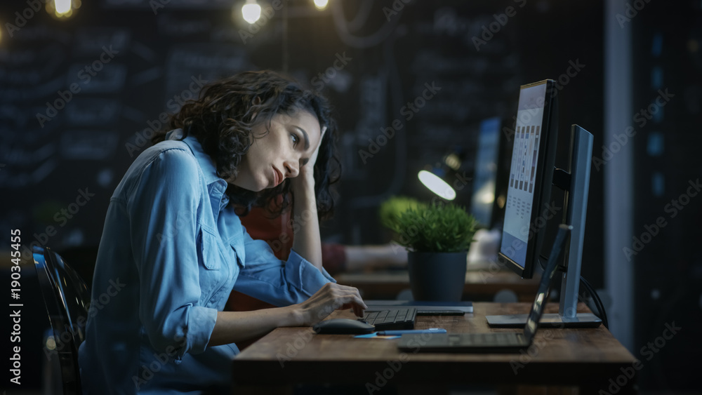 Tired, Overworked Female Financier Holds Her Head in Hands while Working on a Personal Computer. In 