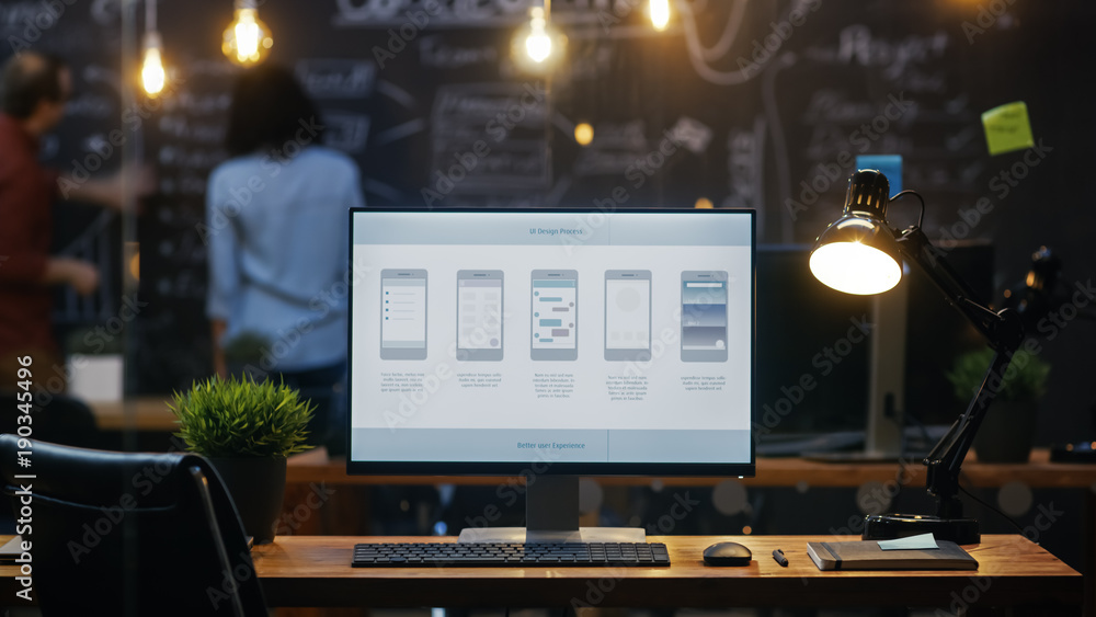 Personal Computer with Mobile Application Design Showing on the Monitor Stands on the Office Desk, I