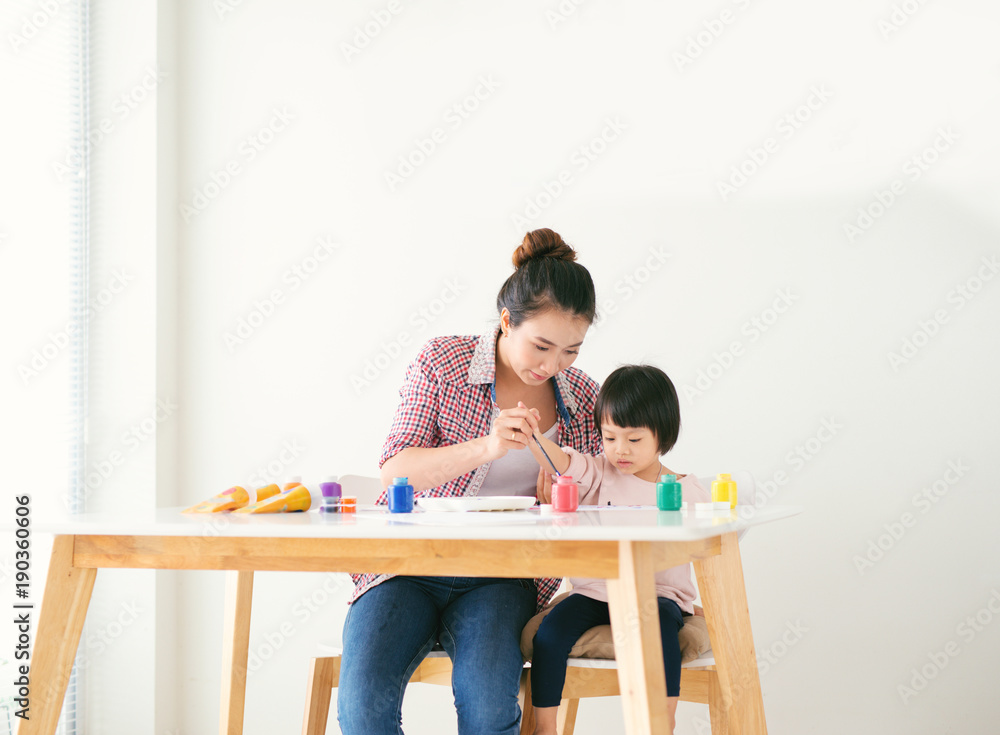 一个幸福的家庭正在画画。妈妈帮女儿画画