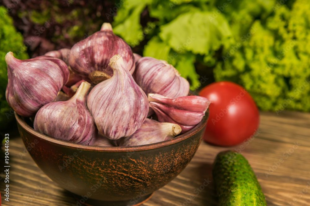 Food ingredients. Garlic on the table. Fresh herbs in the background