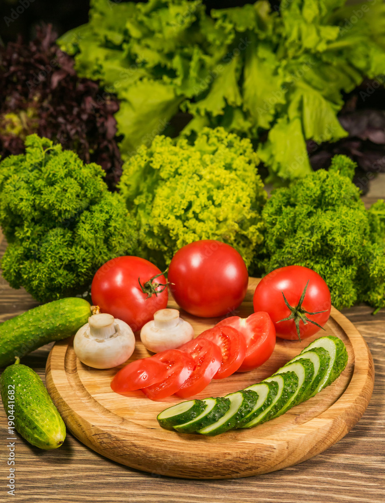 Fresh organic vegetables on a table. Tomatoes, cucumbers, garlic and green basil leaves. Preparation