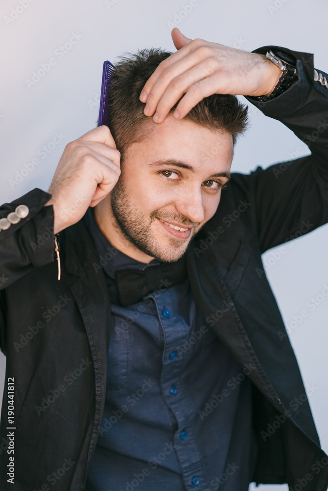 Portrait of a stylish handsome man in formal attire touching his hair. Young man combing his hair