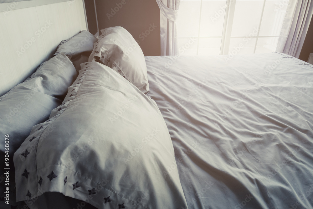 Bed maid-up with clean white  pattern pillows and bed sheets in bedroom. Close-up. Lens flair in sun