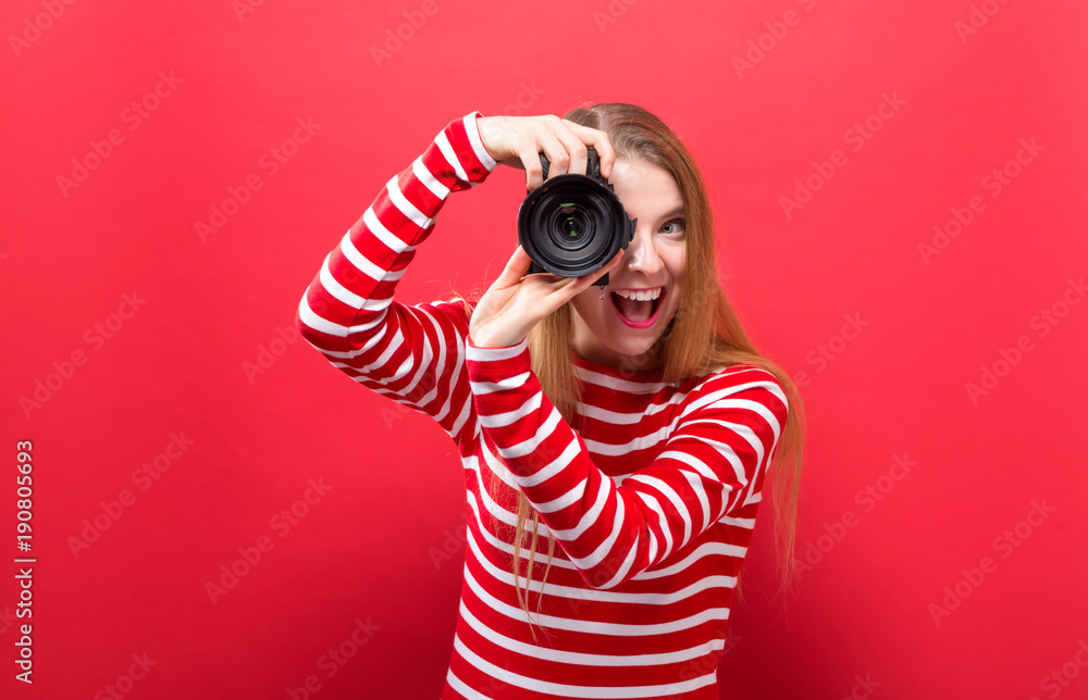 Young woman holding a camera on a solid background