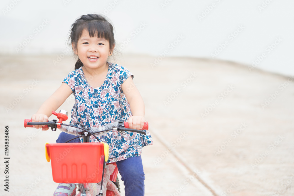 快乐的亚洲小女孩，清晨在家门口骑着自行车。