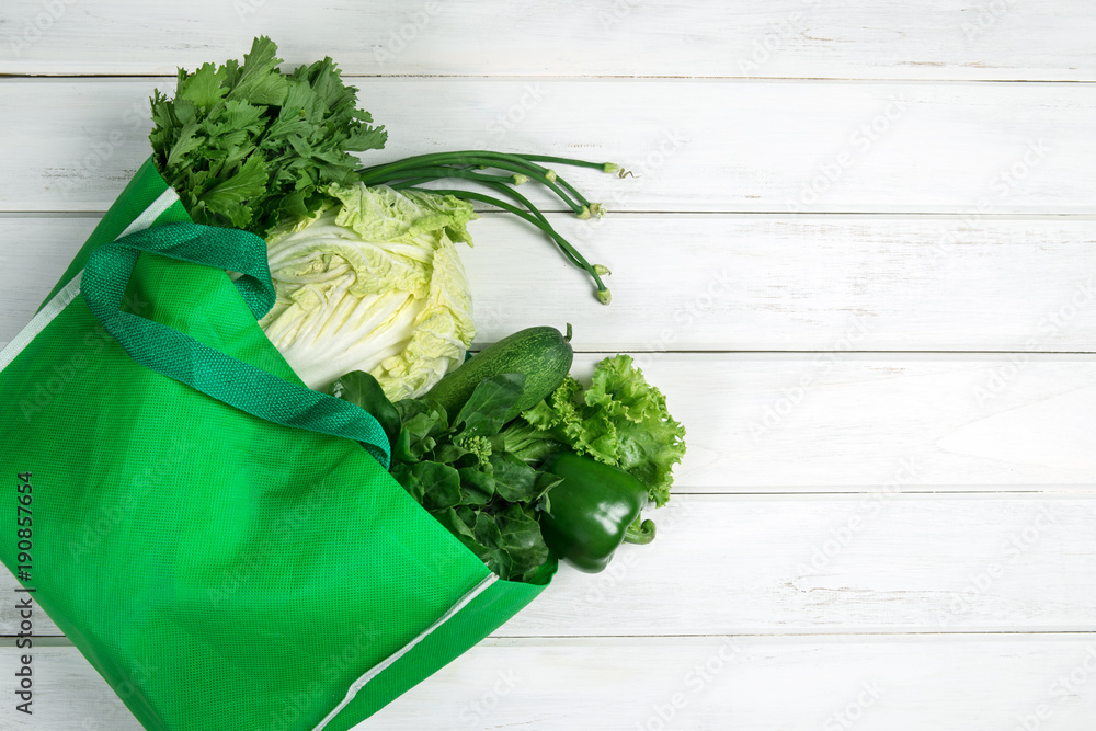 close up a green grocery bag of mixed organic green vegetables on white , healthy organic green food