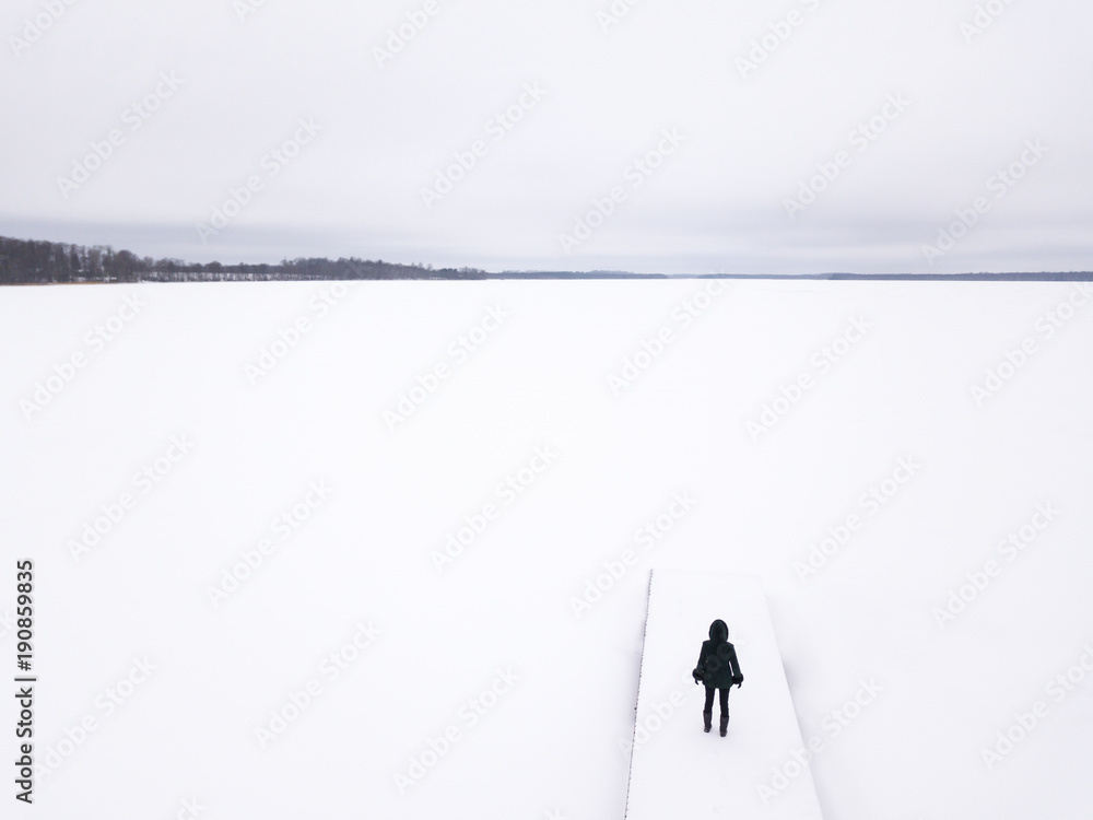 Lonely woman standing on the edge of a snow covered frozen lake. Tartu, Estonia.